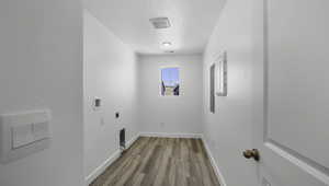 Laundry area with light wood finished floors, hookup for a washing machine, electric dryer hookup, a textured ceiling, and laundry area