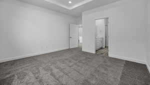 Unfurnished bedroom featuring light carpet, baseboards, ensuite bathroom, and recessed lighting