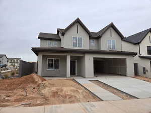 View of front of home with a garage, concrete driveway, covered porch, and stucco siding