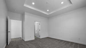 Unfurnished bedroom with carpet floors, recessed lighting, a raised ceiling, and baseboards