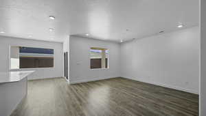 Unfurnished living room featuring a textured ceiling, recessed lighting, wood finished floors, and baseboards