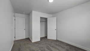 Unfurnished bedroom with carpet floors, a closet, and baseboards