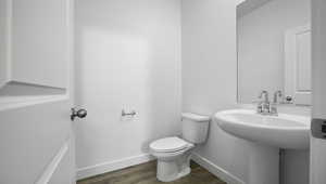 Half bath with wood finished floors, toilet, and baseboards