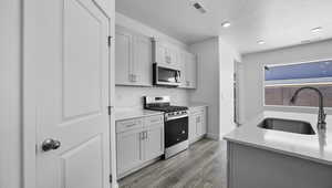 Kitchen with light wood-style flooring, stainless steel appliances, a sink, visible vents, and light countertops