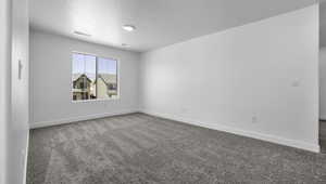 Carpeted spare room featuring visible vents, a textured ceiling, and baseboards