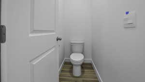 Bathroom featuring wood finished floors, toilet, and baseboards