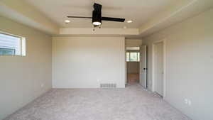 Carpeted spare room with baseboards, visible vents, a raised ceiling, and recessed lighting