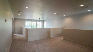 Carpeted spare room with baseboards, visible vents, a textured ceiling, and recessed lighting