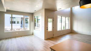 Foyer entrance featuring a textured ceiling, baseboards, visible vents, and light wood-style floors