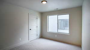 Spare room featuring light carpet, baseboards, and visible vents