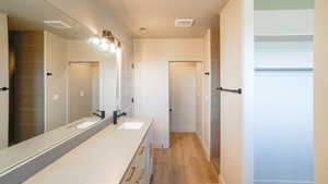 Bathroom featuring visible vents, vanity, and wood finished floors