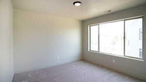 Unfurnished room with baseboards, visible vents, and light colored carpet