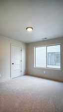 Spare room featuring carpet, visible vents, and baseboards