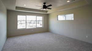 Carpeted empty room with baseboards, visible vents, and a raised ceiling