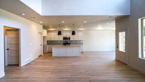 Kitchen with visible vents, white cabinetry, open floor plan, light wood-type flooring, and stainless steel microwave