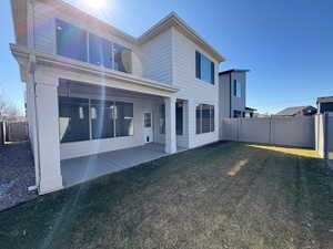 Rear view of house featuring a fenced backyard, a lawn, and a patio