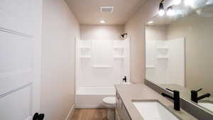 Bathroom with visible vents, shower / bath combination, toilet, vanity, and wood finished floors