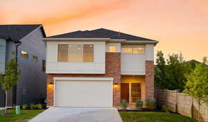 View of front of property with concrete driveway, brick siding, fence, and stucco siding