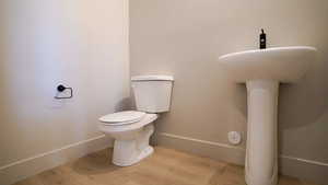 Bathroom with wood finished floors, toilet, and baseboards