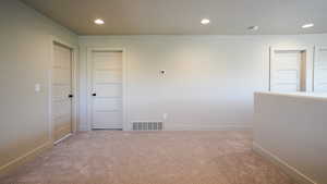 Carpeted empty room featuring baseboards, visible vents, and recessed lighting