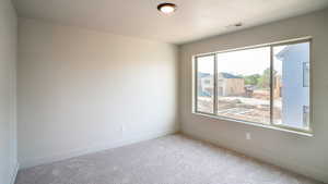 Carpeted empty room with visible vents and baseboards