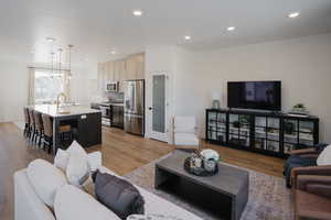 Living area with an inviting chandelier, light wood-style flooring, baseboards, and recessed lighting