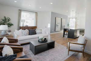 Living area featuring baseboards, light wood-style flooring, and recessed lighting