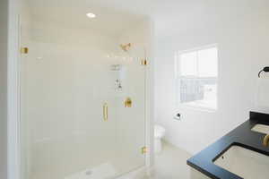 Full bath featuring a sink, a shower stall, toilet, and double vanity