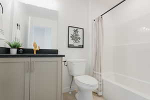 Full bathroom with shower / bath combo, baseboards, toilet, tile patterned flooring, and vanity