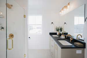 Bathroom with double vanity, a shower stall, baseboards, and a sink