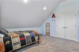 Bedroom with carpet, a closet, lofted ceiling, and baseboards