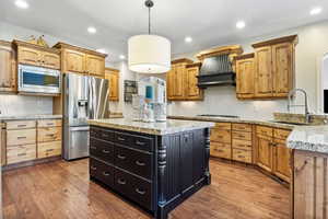 Kitchen featuring stainless steel appliances, a center island, a sink, and wood finished floors