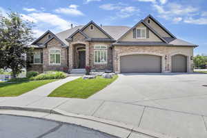 Craftsman-style home featuring driveway, a front yard, an attached garage, and stucco siding