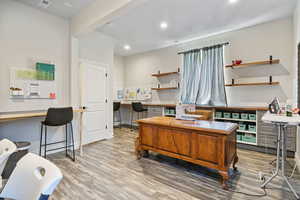 Office featuring wood finished floors, built in study area, visible vents, and recessed lighting