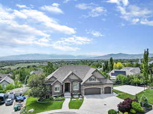View of front of home with a shingled roof, a mountain view, fence, a garage, and a front lawn