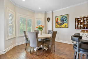 Dining room with recessed lighting, wood-type flooring, crown molding, and baseboards