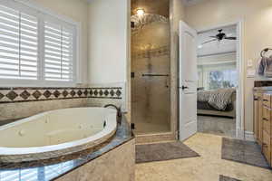 Bathroom with ornamental molding, connected bathroom, a shower stall, and a whirlpool tub