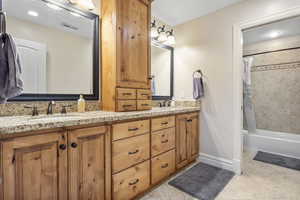 Bathroom featuring double vanity, shower / bathtub combination with curtain, a sink, and tile patterned floors
