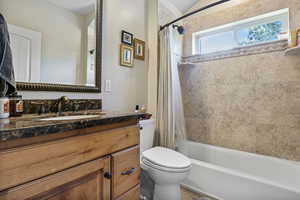 Bathroom featuring toilet, shower / tub combo with curtain, and vanity