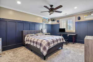 Bedroom with carpet, visible vents, a decorative wall, and ornamental molding