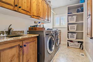 Washroom featuring separate washer and dryer, a sink, visible vents, baseboards, and cabinet space