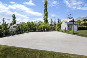 View of basketball court with a yard, fence, and basketball court