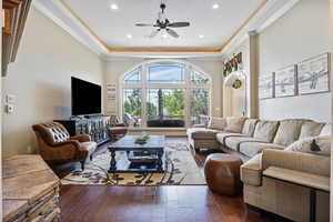 Living room with ornamental molding, wood-type flooring, and a ceiling fan
