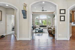 Interior space with a ceiling fan, baseboards, arched walkways, and hardwood / wood-style floors