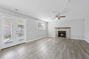 Unfurnished living room with a textured ceiling, french doors, wood finished floors, and visible vents