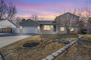 Traditional-style home with a garage, fence, concrete driveway, and brick siding