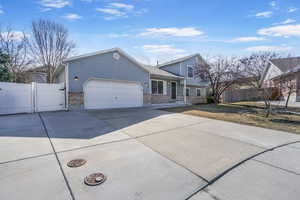 View of front facade with an attached garage, a gate, fence, and concrete driveway