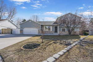 View of front of house with a garage, driveway, fence, and brick siding