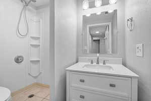 Full bath featuring tile patterned flooring, vanity, walk in shower, and a textured wall