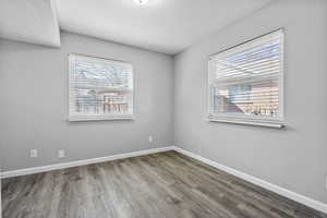 Empty room with a wealth of natural light, baseboards, and wood finished floors